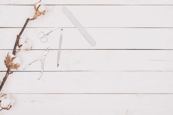 Vue de dessus des outils de manucure sur table en bois avec brindille en coton — Photo de stock