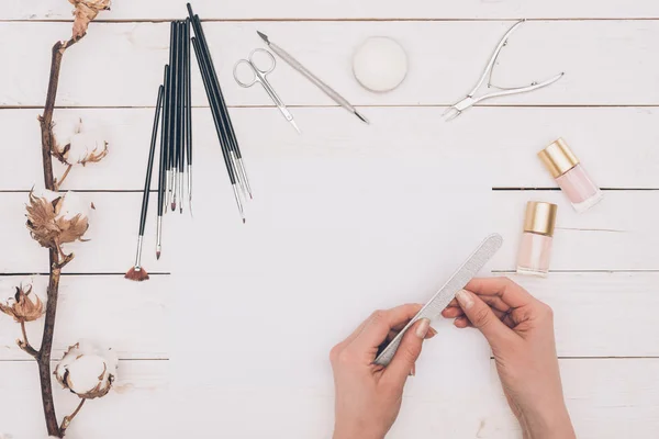 Cropped image of woman filing nails with nail file — Stock Photo