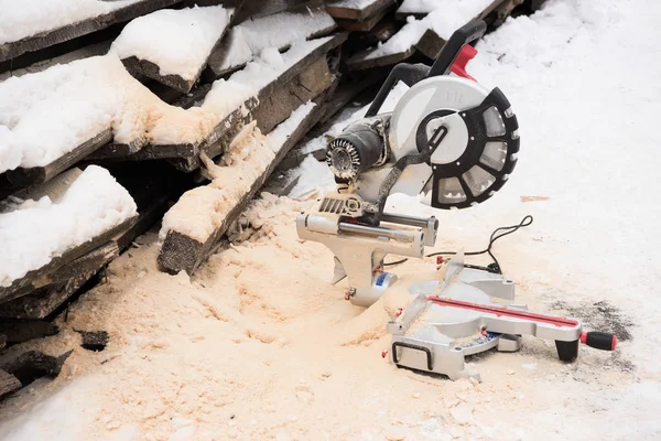 Saw-blade and firewood covered with snow — Stock Photo
