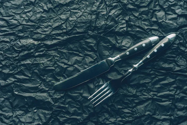 Cerrar ver tenedor de acero y cuchillo en la superficie de textura oscura - foto de stock