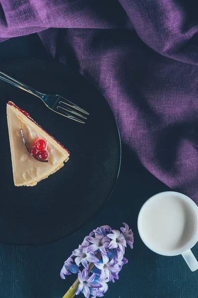 Top view of piece of cake on plate and cup of milk on dark surface — Stock Photo