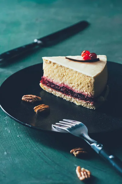 Close up view of piece of cake on plate with hazelnuts and fork — Stock Photo