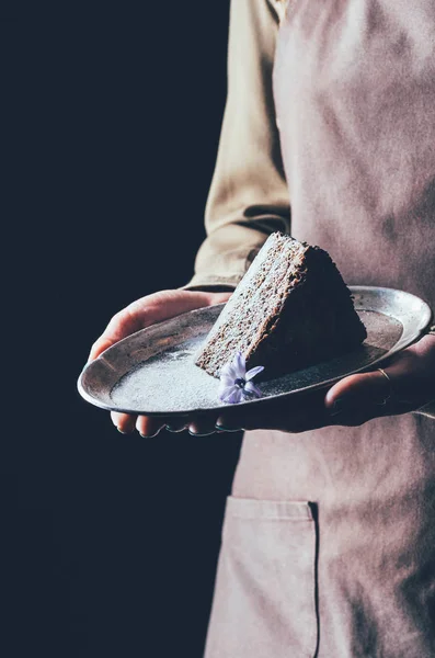 Close up view of woman holding piece of homemade cake on plate in hands — Stock Photo