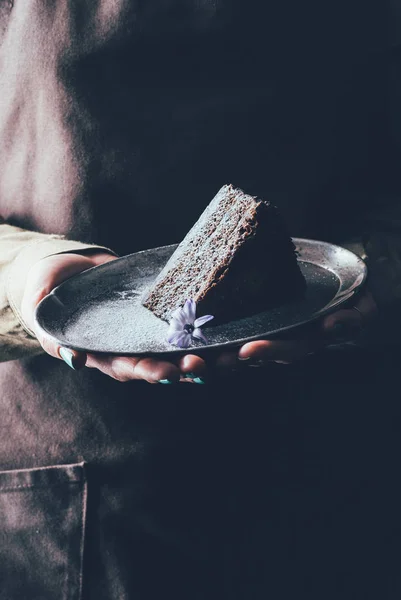 Nahaufnahme einer Frau, die ein Stück hausgemachten Kuchen auf einem Teller in den Händen hält — Stockfoto