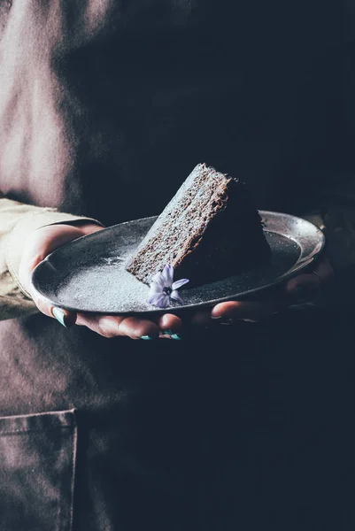 Close up view of woman holding piece of homemade cake on plate in hands — Stock Photo