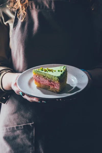 Nahaufnahme einer Frau, die ein Stück hausgemachten Kuchen auf einem Teller in den Händen hält — Stockfoto