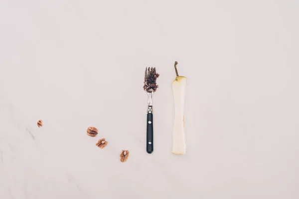 Vista superior do garfo arranjado, avelãs e núcleo de pêra na mesa — Fotografia de Stock