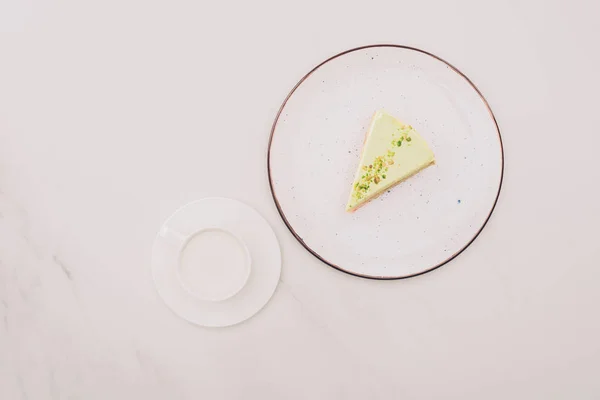 Top view of piece of cake on plate and cup of milk on white surface — Stock Photo