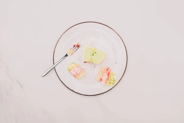 Top view of pieces of cake on plate and fork on tabletop — Stock Photo