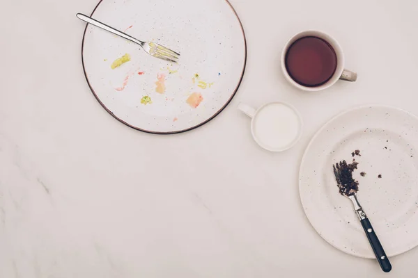 Top view of arranged plates with pieces of cakes and drinks on white tabletop — Stock Photo