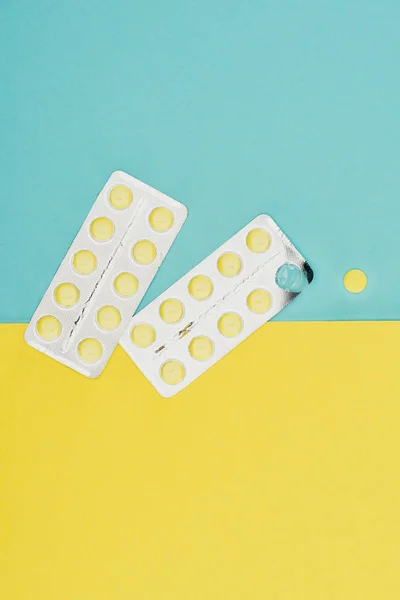 Top view of medicines isolated on blue and yellow background — Stock Photo