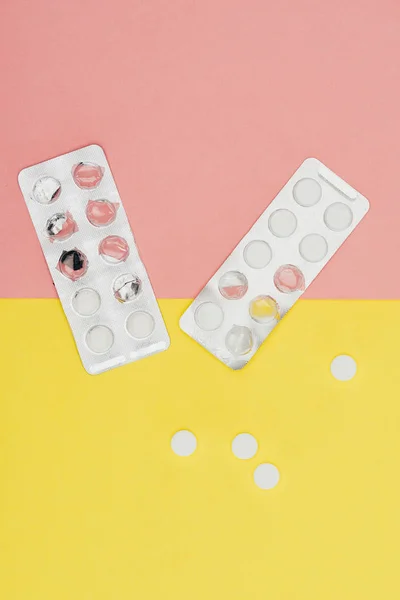 Vista superior de pílulas isoladas em fundo rosa e amarelo — Fotografia de Stock