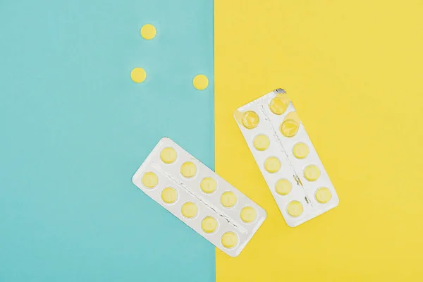 Vista superior de medicamentos isolados em fundo azul e amarelo — Fotografia de Stock