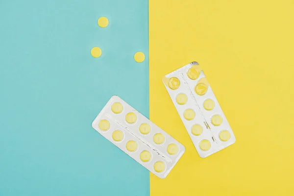 Vue du dessus des médicaments isolés sur fond bleu et jaune — Photo de stock