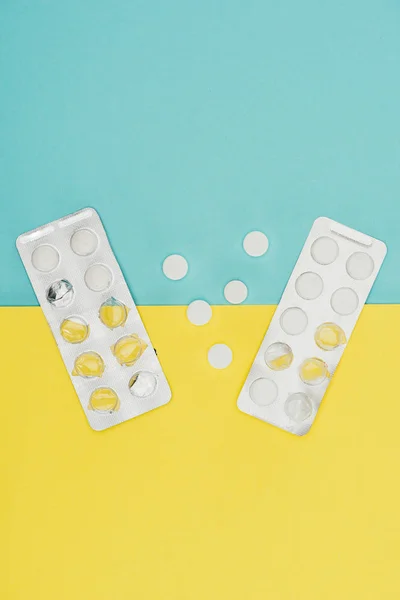 Vista superior de los medicamentos aislados sobre fondo azul y amarillo - foto de stock