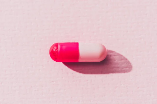 Close up view of pink medicine on pink surface — Stock Photo