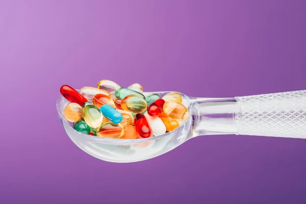 Close up view of medicines in spoon isolated on purple — Stock Photo