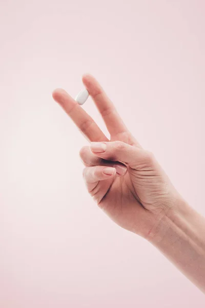 Vista parcial de la mujer que sostiene la medicina en la mano aislada en rosa - foto de stock