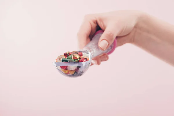 Vista parziale di donna che tiene pillole in cucchiaio isolato su rosa — Foto stock