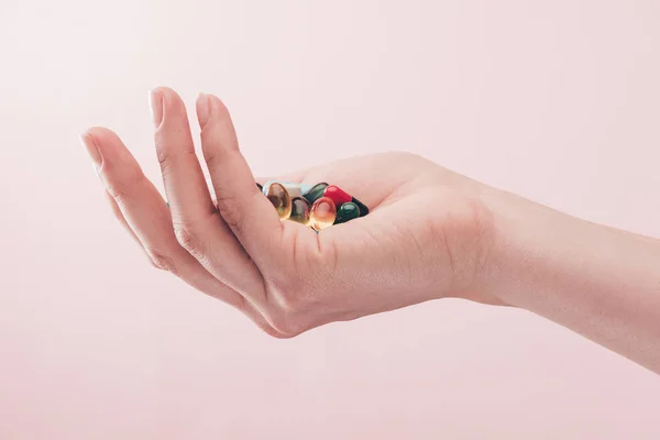 Partial view of woman holding pills in hand isolated on pink — Stock Photo