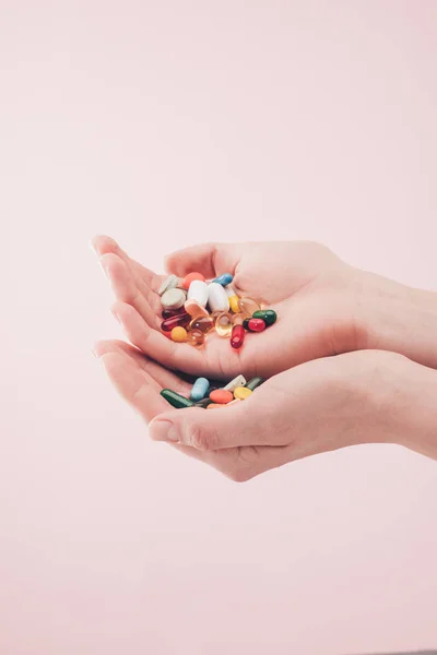 Vue partielle de la femme tenant des pilules dans les mains isolées sur rose — Photo de stock