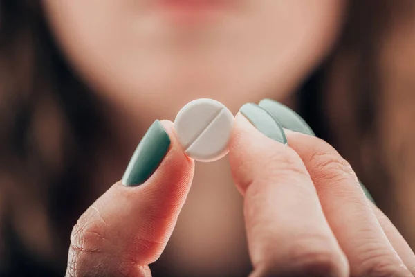 Частковий вид жінки, що показує таблетку в руці — стокове фото