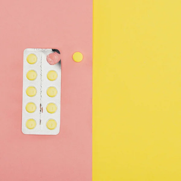 Vista superior de las píldoras aisladas sobre fondo rosa y amarillo - foto de stock