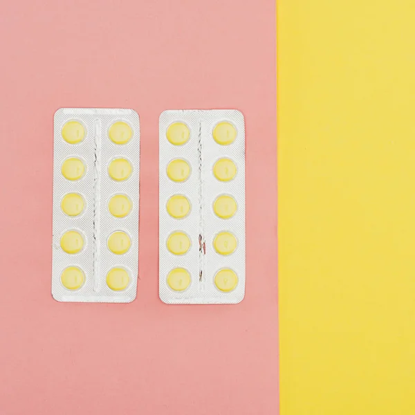 Vista superior de las píldoras aisladas sobre fondo rosa y amarillo - foto de stock