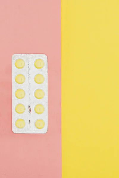Vista superior de las píldoras aisladas sobre fondo rosa y amarillo - foto de stock