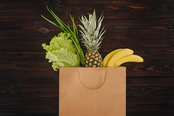 Vista dall'alto di cavolo cinese, ananas e banane nella shopping bag sul tavolo di legno — Foto stock