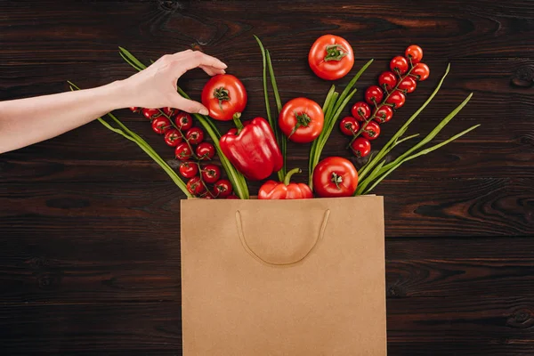 Imagen recortada de chica tomando tomate de la bolsa de compras - foto de stock