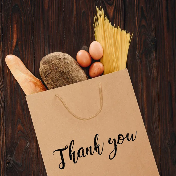 Сверху вид на хлеб, макароны и яйца в бумажном пакете со словами спасибо, концепция продуктовый — стоковое фото