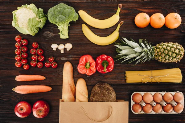 Blick von oben auf Gemüse und Obst, Brot und Eier auf Holztisch, Lebensmittelkonzept — Stockfoto