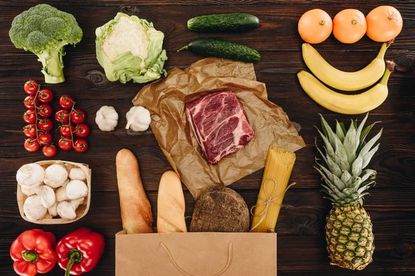 Vista superior de la carne cruda con verduras y frutas en la mesa de madera, concepto de supermercado - foto de stock