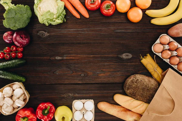 Top view of vegetables and fruits with bread and pasta on wooden table, grocery concept — Stock Photo