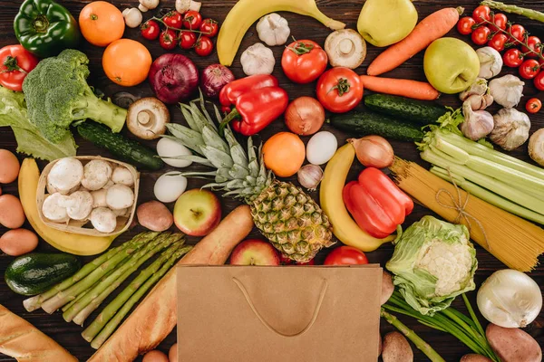 Vista superior do saco de compras com legumes e frutas na mesa de madeira — Fotografia de Stock