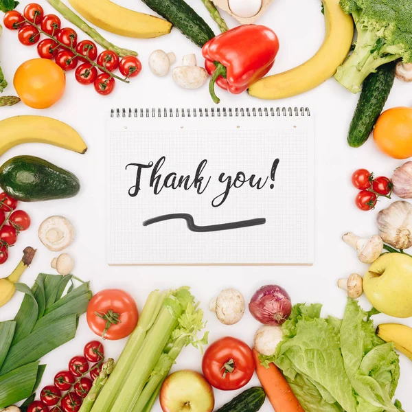 Top view of notebook with words thank you between vegetables and fruits isolated on white — стоковое фото