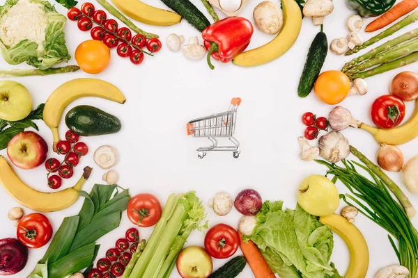 Top view of shopping cart between vegetables and fruits isolated on white, grocery concept — Stock Photo