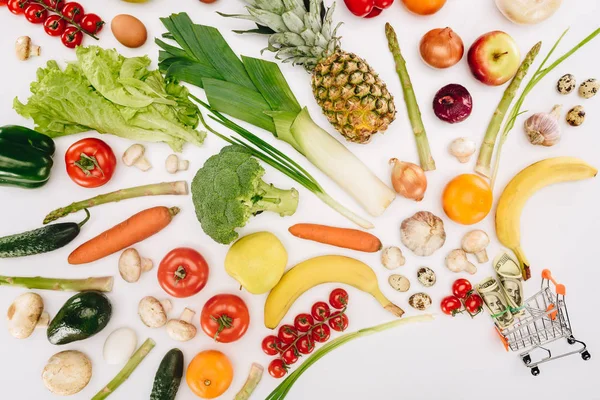 Vista superior del pequeño carrito de compras con dólares y frutas con verduras aisladas en blanco - foto de stock