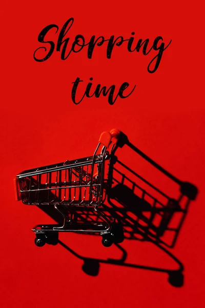 Ein Warenkorb mit Schatten auf roter Wand und Wörtern Einkaufszeit — Stockfoto