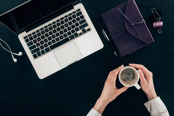 Cropped shot of businesswoman drinking coffee at workplace isolated on black — Stock Photo