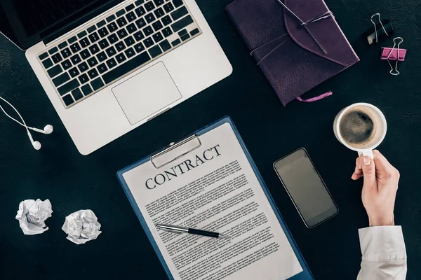 Cropped shot of businesswoman drinking coffee at workplace with contract isolated on black — Stock Photo