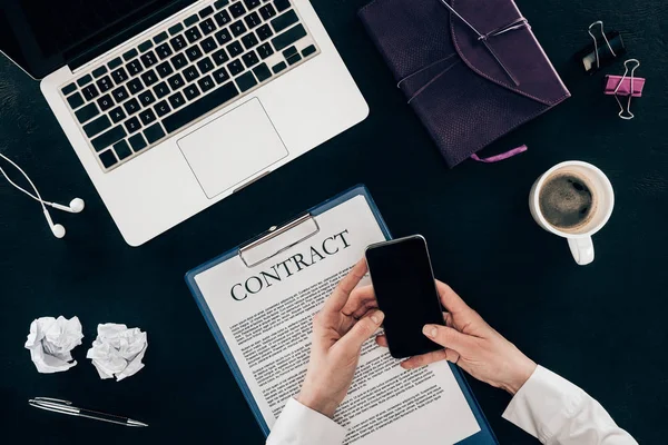 Cropped shot of businesswoman using smartphone at workplace isolated on black — Stock Photo