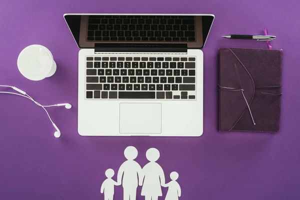 Вид на рабочее место с вырезанными семейными фигурами на фиолетовой поверхности, концепция семейного страхования — стоковое фото