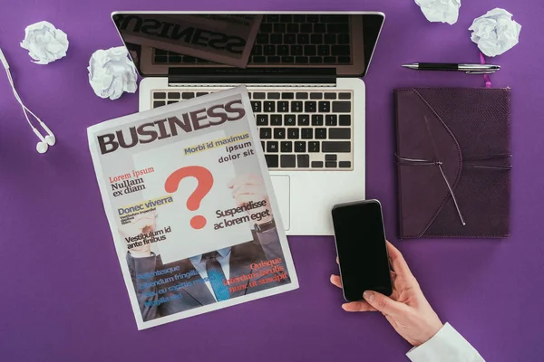 Cropped shot of businesswoman using smartphone at workplace on purple surface — Stock Photo