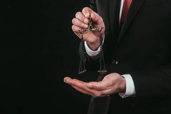 Cropped shot of lawyer holding mini scales isolated on black — Stock Photo