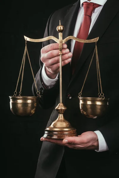 Cropped shot of lawyer holding justice scales isolated on black — Stock Photo