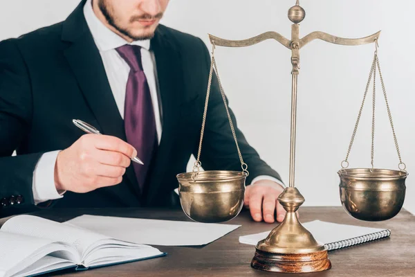 Tiro cortado de advogado fazendo papelada no local de trabalho com escalas — Fotografia de Stock