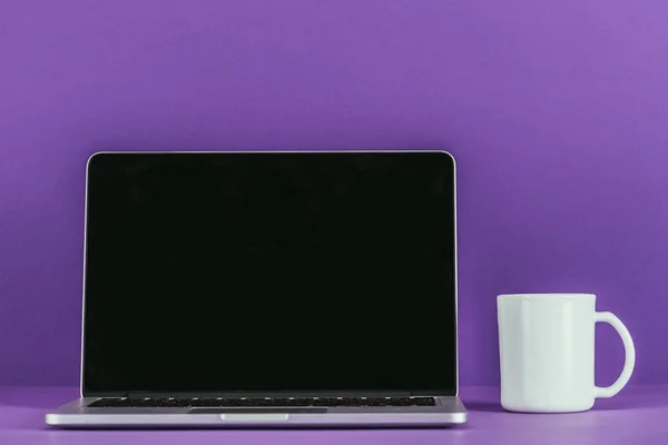 Posto di lavoro con laptop e tazza di caffè sulla superficie viola — Foto stock