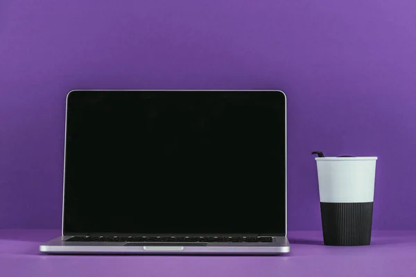 Laptop com xícara de papel de café na superfície roxa — Fotografia de Stock